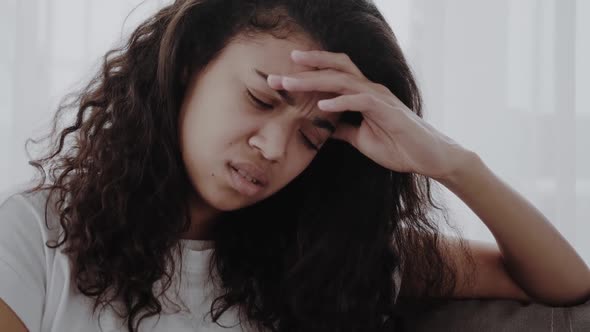 African Young Woman Sit on Couch Frown Face Expressions Touches Temples Reduces Sharp Severe