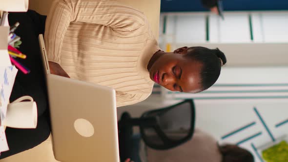 African American Lady Writing on Laptop Looking at Camera Smiling