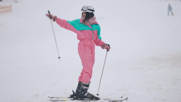 Wide Shot of Happy Slim Woman in Ski Suit Waving and Riding Away on Snowy Slopes