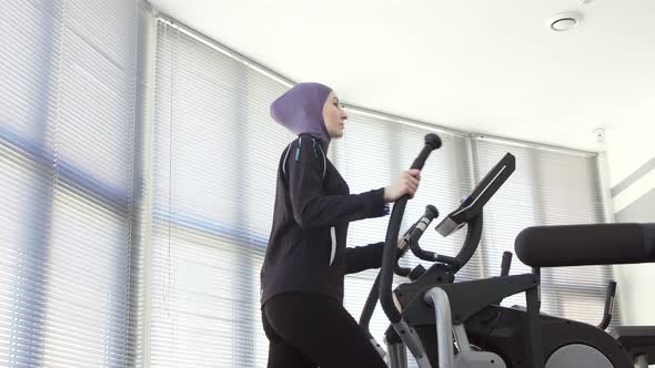 Portrait of a Sports Girl in a Hijab on a Step Simulator Fitness Muslim