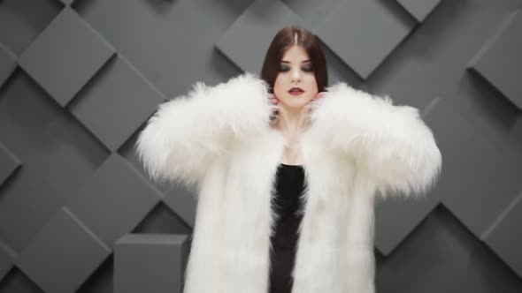 Young Woman in Putting on White Fur Coat and Readjust Her Hair