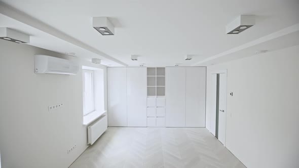 Camera Panning Right Inside Empty Room with White Walls and Fitted Wardrobe in Modern Apartment -