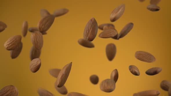 Close-up of Delicious Almonds Flying Up and Rotating on the Yellow Background