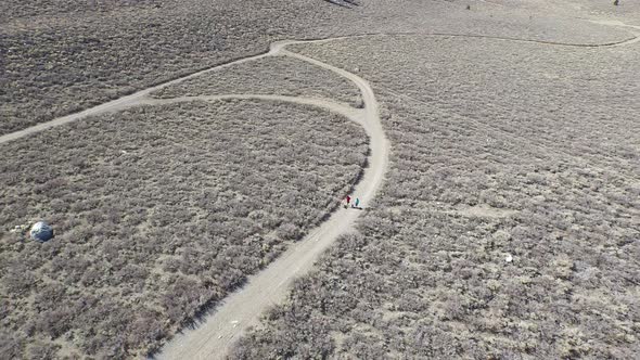 Aerial shot of a young man and woman trail running with dog on scenic mountain trail