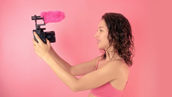 Young Woman Vlogger Recording Broadcast in Slow Motion on a Pink Background