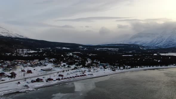 Flying over a small village and Lyngenfjord in Lyngen Alps, Norway, Arctic