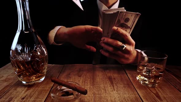 Wealthy Man in an Elegant Black Suit Rests in a Bar and Splashes Money in Slow Motion