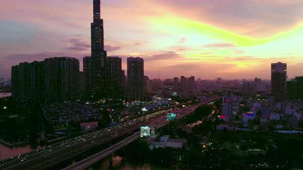 Sky on fire at city sunset, lots of traffic over Saigon Bridge; drone view