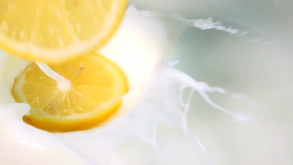 Pieces of Lemon Drops Into the Milk. Slowmotion