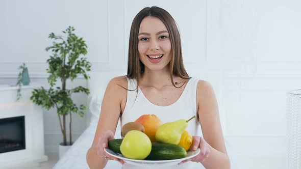 Attractive Caucasian Woman Stretching Out Plate With Fruits to the Camera