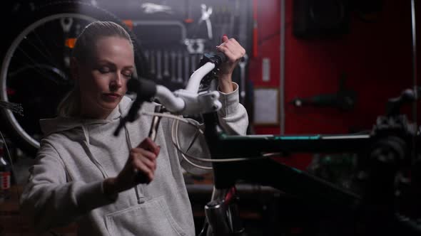 Portrait of Attractive Woman Bike Repairman Tightening Bolt on Handlebars of Broken Mountain Bicycle