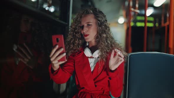 A Smiling Curly Woman is Having a Video Call in Bus