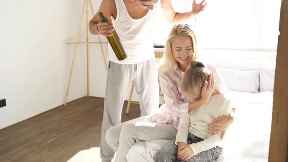 Drunk Father with an Empty Bottle in His Hand Yells at His Wife and Child