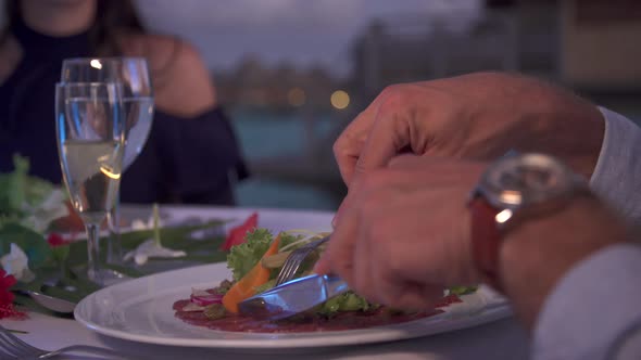 A man and woman couple dining outside at dinner at a tropical island resort