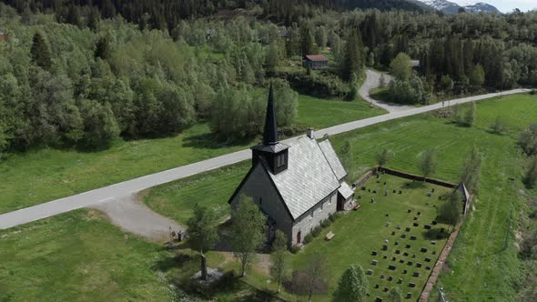 Aerial ascending over beautiful Stone Church on evergreen valley, Bergsdalen - Norway