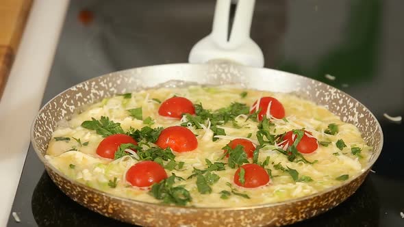 Cooking Egg Omelet with Cherry Tomatoes in a Frying Pan