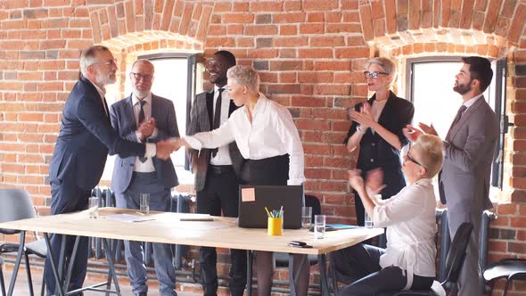 Group of Businessmen in Office Congratulate Colleague Who Sit at Table and Work To Laptop.