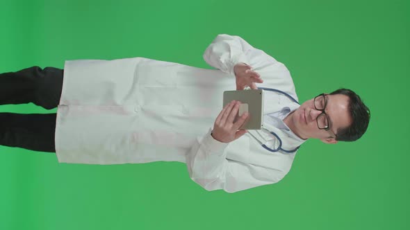 Asian Doctor With Stethoscope Using Tablet While Walking On Green Screen Chroma Key