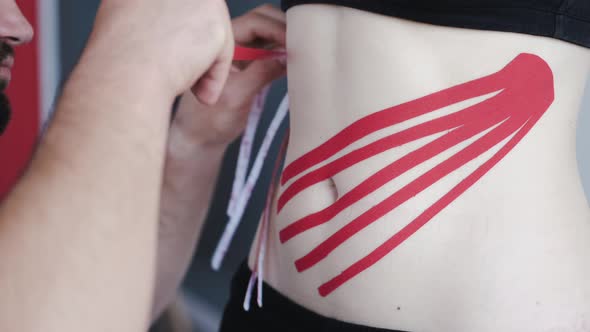 Person with Red Kinesiology Tape on Stomach in Private Clinic