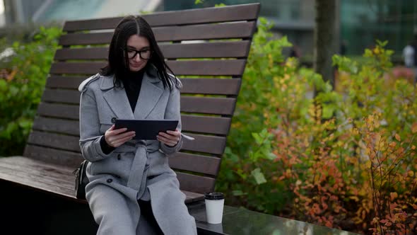 Adult Woman is Surfing Internet By Tablet in Park in Autumn Day