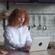 Young Redhaired Woman with Curly Hair Sitting at Home Kitchen Getting and Reading Congratulations - VideoHive Item for Sale