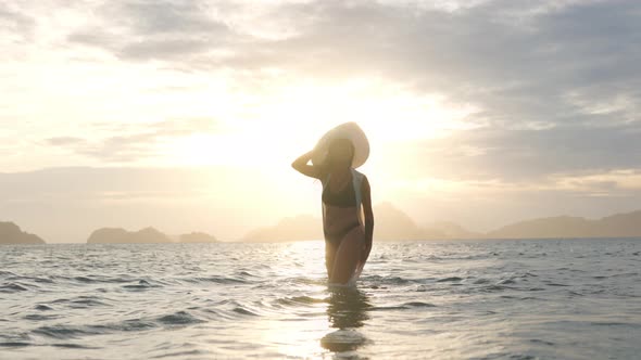 Woman In Thong In Sea Facing Glowing Sunset