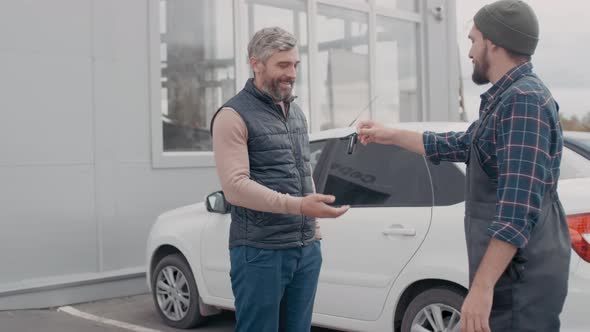 Auto Mechanic Returning Car Keys to Happy Client