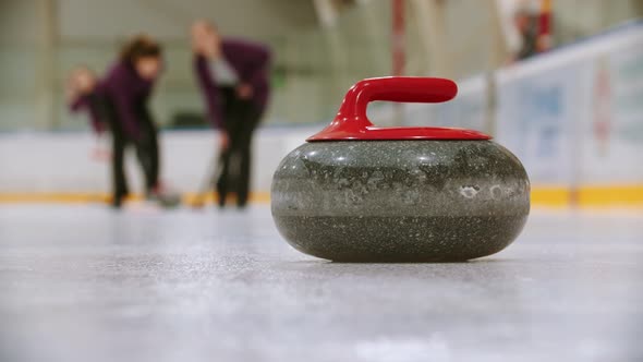 Curling Training - Leading Granite Stone on the Ice - Two Women Rubbing the Ice Before the Stone 