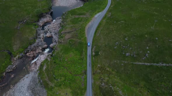 Car drives down remote country road in mountainous area