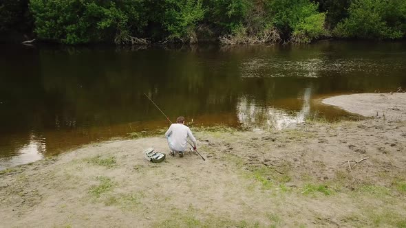 Fisherman with a Fishing Rod on the River Bank