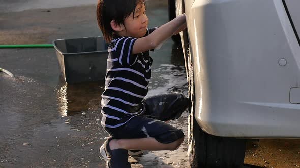 Asian Child Washing Car In The Garden On Summer Day