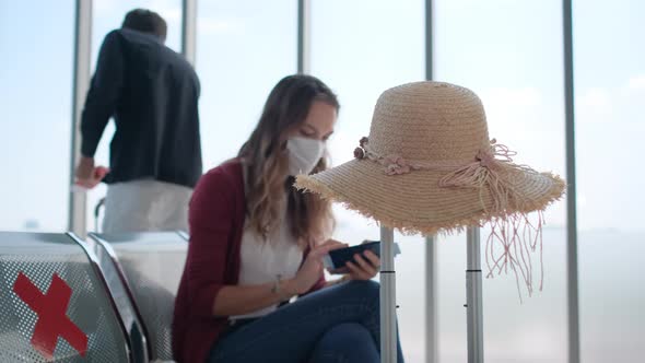 Man with hygiene mask bring suitcase go to sit on back row of waiting chair behind of woman