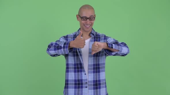 Confused Bald Hipster Man Choosing Between Thumbs Up and Thumbs Down