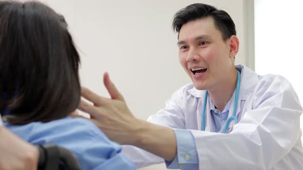 Asian male doctor Examine the symptoms of a patient sitting in a wheelchair.