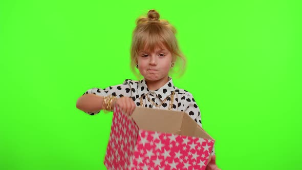 Child Girl Unwrapping Birthday Gift and Expressing Disappointment Dislike Bad Present Dissatisfied