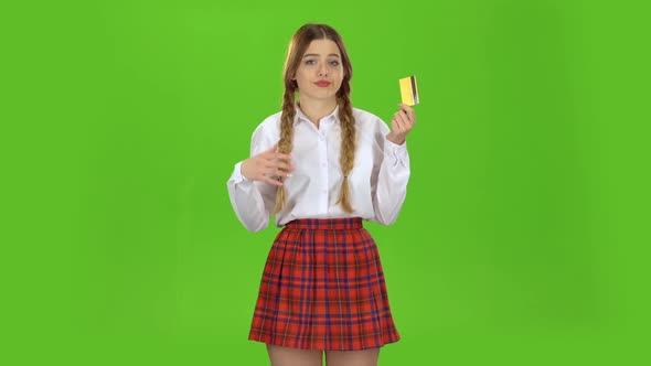 Schoolgirl with a Credit Card in Her Hands Is Sad. Green Screen