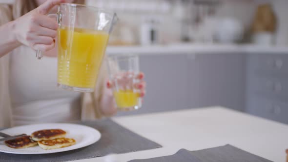 Woman Pouring Orange Juice into Glass