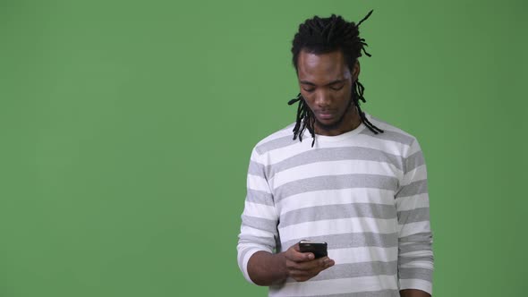 Young Handsome African Man with Dreadlocks Against Green Background