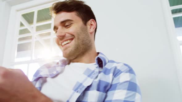 Man using mobile phone while relaxing on sofa