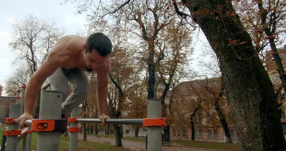 Young Man Is Doing Two Handstand on Bars Outside in Autumn Day 