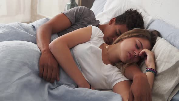 Closeup View of Multiracial Couple Lying in Bed and Sleeping While Embracing Each Other