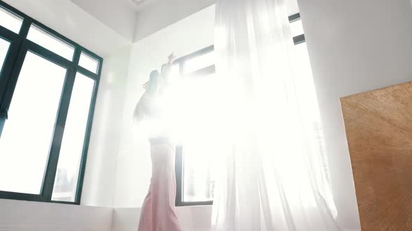 A Young Woman Dances in Front of a Window in Bright Daylight