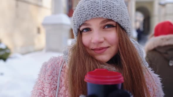 Stylish Woman Traveler with Hot Drink in Cup Looking Around Through City Street During Vacations