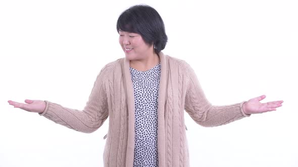 Happy Overweight Asian Woman Comparing Something Ready for Winter