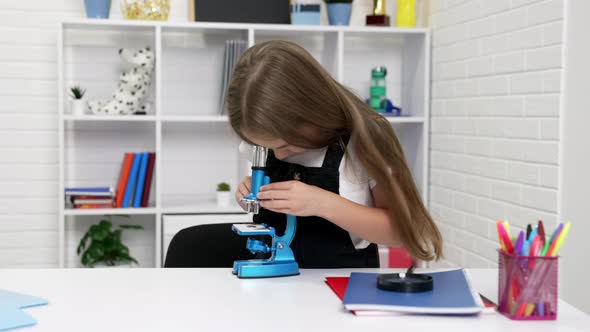 Concentrated Teen Girl Looking Through Modern Scope on Chemistry Lesson Knowledge