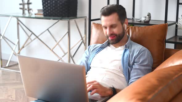 A Focused Man Wearing Casual Shirt Using a Laptop for Video Call