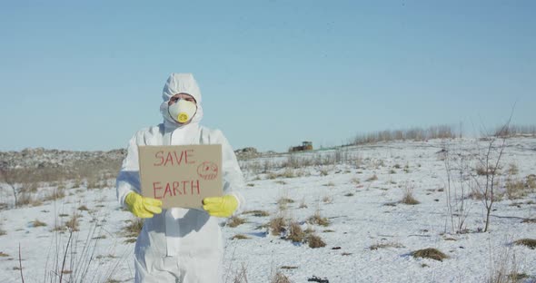 Man Wore in Protective Suit Shows Save Earth Sign on Abandoned Place in Winter