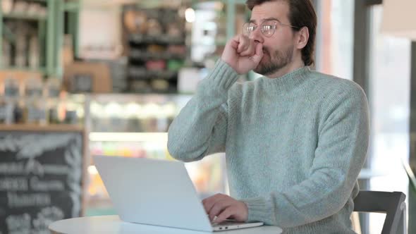 Young Man Coughing While Working on Laptop