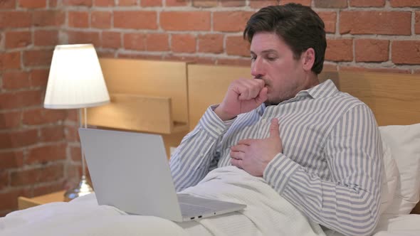 Middle Aged Man with Laptop having Coughing in Bed