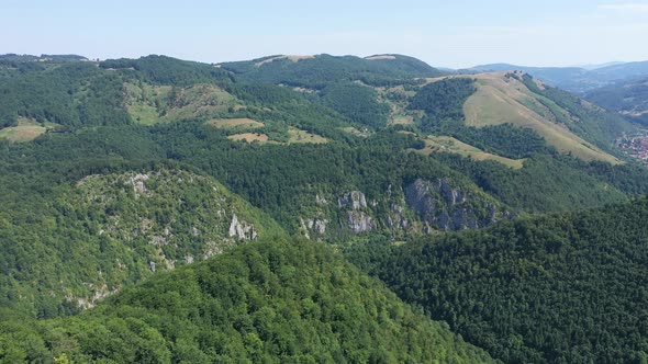 Flying Above a Deep Valley With a Small Village, Deciduous Forest. Aerial Shot